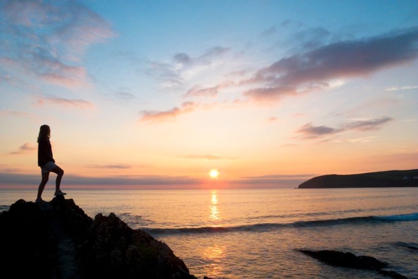 silhouette-of-a-woman-standing-on-a-rock-and-looki-w900-h675