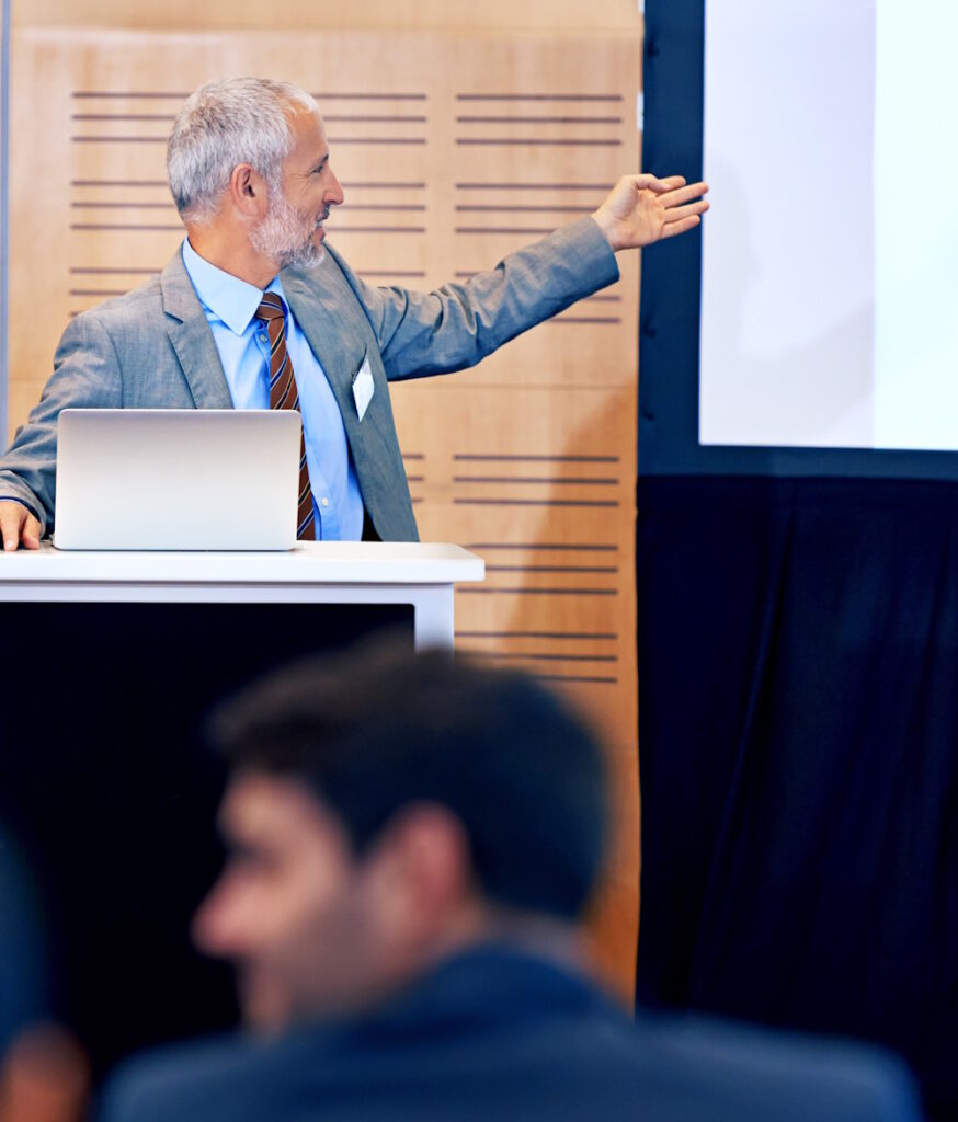 Older instructor pointing to a flip chart while leading an AI workshop